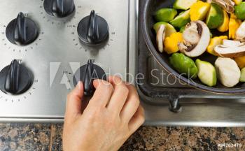 Hand turning on stove